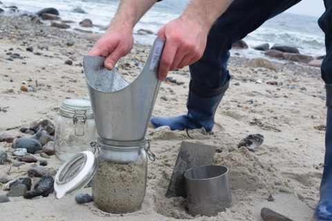 Kevin Schröder überführt die Sedimentprobe in ein Einmachglas. Foto: Dennis Brennecke