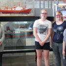 “Smoke under water” girls and their group leader in front of miniature models of the old and new research vessel RV Sonne. / „Smoke under water“ Mädels und ihre Projektbetreuerin vor den Miniaturmodellen des alten und neuen Forschungsschiff FS Sonne. (© M. Klischies)