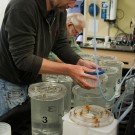 Henk-Jan carries sample buckets to the wet table in the wet lab on the Western Flyer. Copyright: MBARI